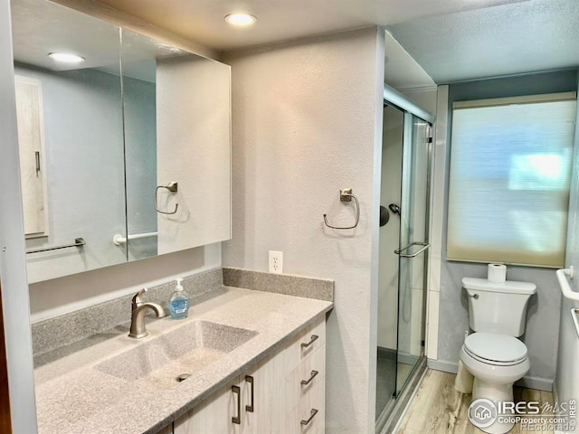 full bathroom with a stall shower, vanity, toilet, and wood finished floors