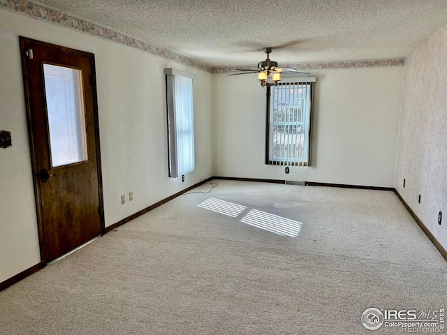 carpeted spare room with visible vents, ceiling fan, a textured ceiling, and baseboards