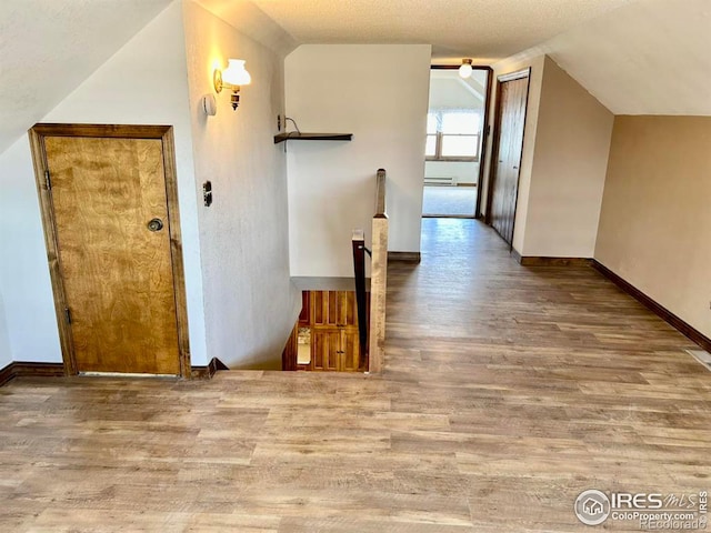 hall with lofted ceiling, an upstairs landing, and wood finished floors