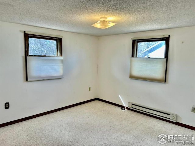 carpeted spare room with a textured ceiling, baseboard heating, and a wealth of natural light