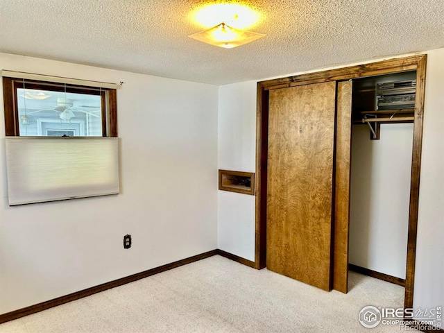 unfurnished bedroom with a textured ceiling, a closet, carpet flooring, and baseboards