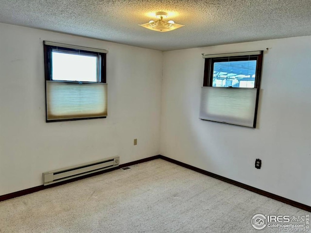 spare room featuring a textured ceiling, baseboard heating, carpet, and baseboards