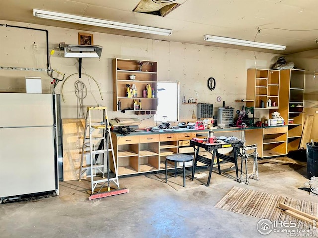 garage with freestanding refrigerator and a workshop area