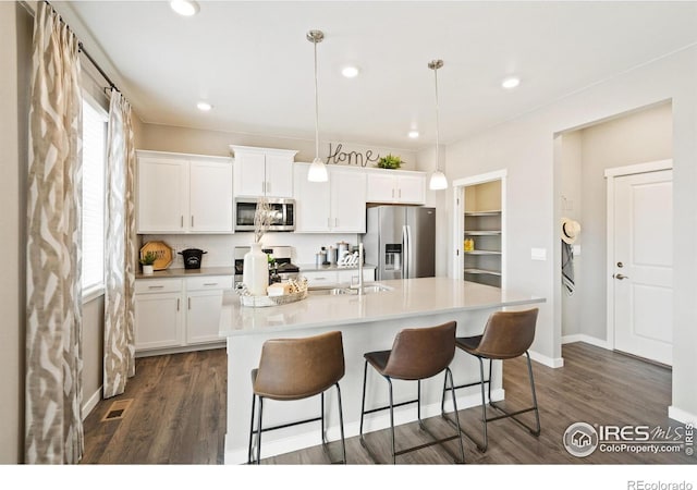 kitchen featuring stainless steel appliances, visible vents, a sink, dark wood-type flooring, and a breakfast bar area
