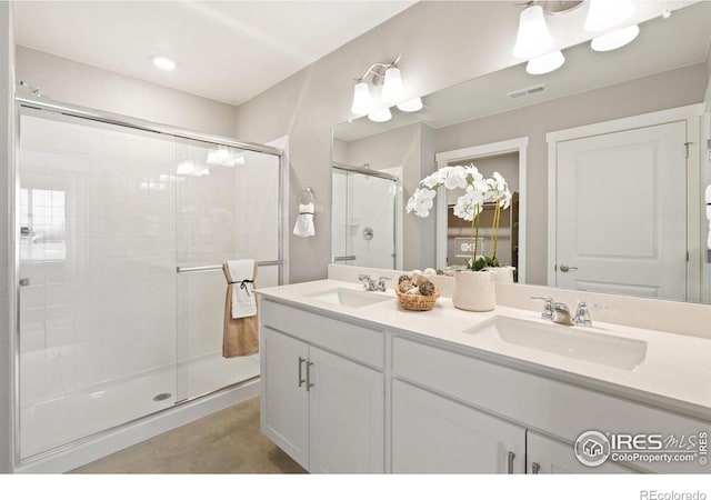 full bathroom featuring a sink, visible vents, a shower stall, and double vanity