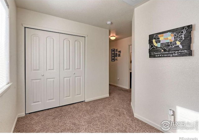 unfurnished bedroom featuring carpet floors, a closet, visible vents, and baseboards