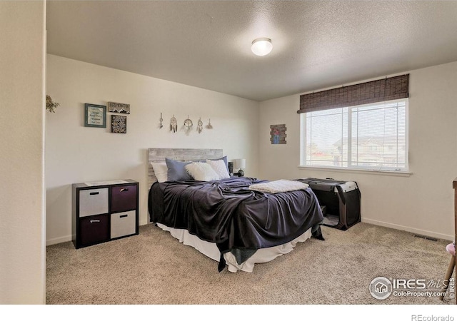 bedroom with a textured ceiling, carpet flooring, and baseboards