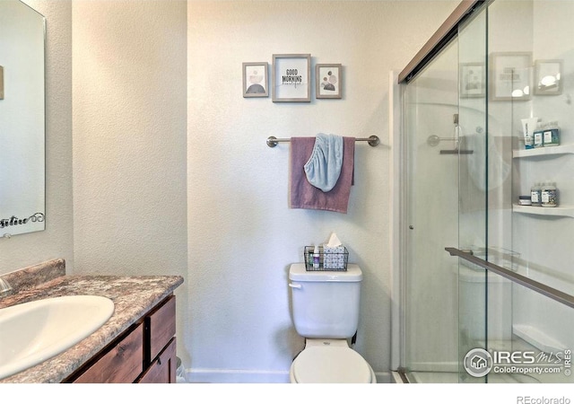 full bathroom featuring a stall shower, vanity, and toilet