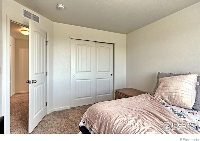 carpeted bedroom with visible vents and a closet