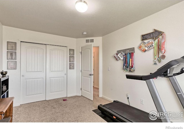 exercise area with carpet, visible vents, a textured ceiling, and baseboards