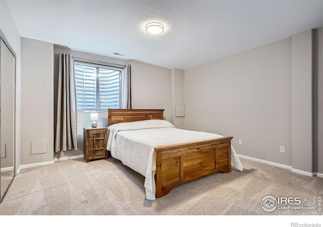 bedroom featuring baseboards, a textured ceiling, and light colored carpet