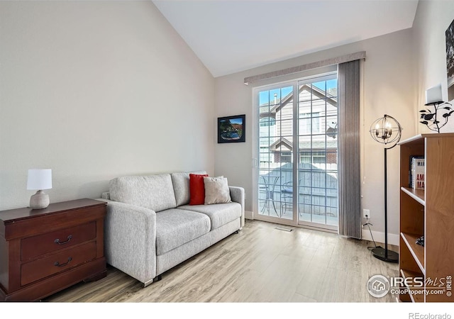 living area with vaulted ceiling, wood finished floors, and baseboards