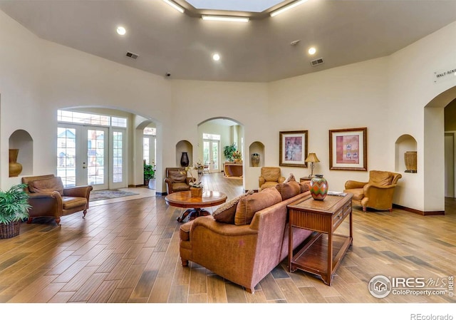 living area featuring french doors, a high ceiling, wood finished floors, and visible vents