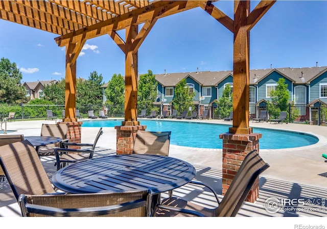 community pool with a patio area, fence, a residential view, and a pergola