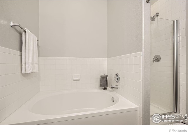 full bathroom featuring a shower stall and a bath