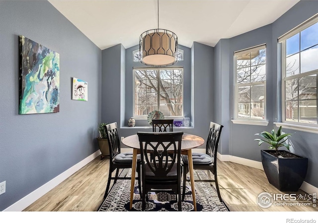 dining area with lofted ceiling, light wood-style flooring, and baseboards