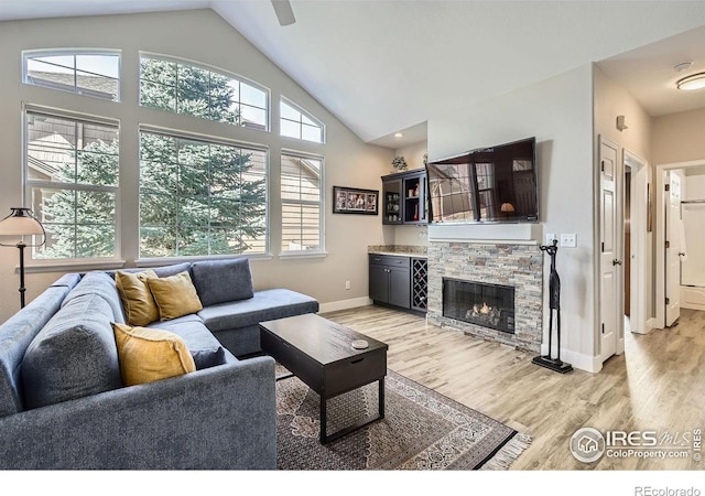 living room with a stone fireplace, light wood finished floors, and a healthy amount of sunlight