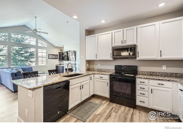 kitchen featuring open floor plan, a peninsula, black appliances, white cabinetry, and a sink