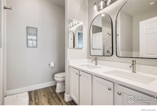 full bath featuring double vanity, a sink, toilet, and wood finished floors