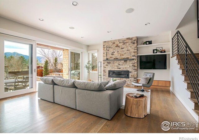 living room with baseboards, stairway, wood finished floors, a fireplace, and recessed lighting