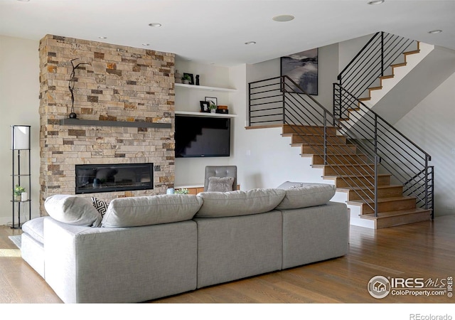 living area featuring stairs, a fireplace, and wood finished floors