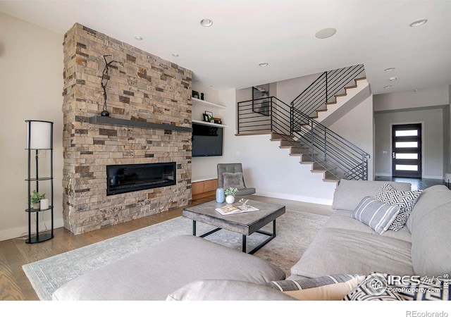 living room featuring baseboards, stairway, wood finished floors, a fireplace, and recessed lighting