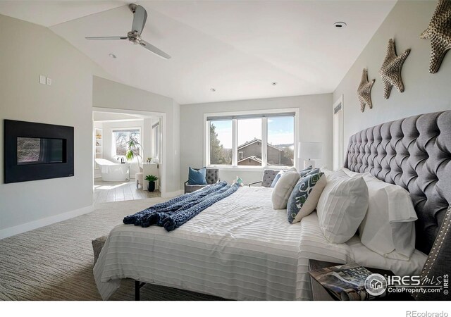 bedroom with carpet floors, a ceiling fan, baseboards, vaulted ceiling, and ensuite bath