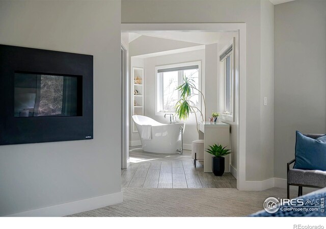 full bath featuring a freestanding tub, baseboards, and wood finished floors