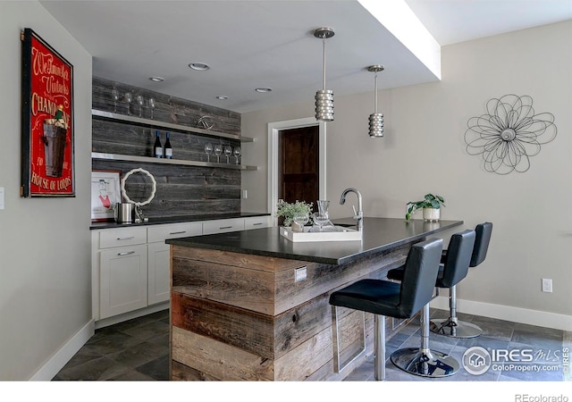 bar featuring baseboards, decorative backsplash, decorative light fixtures, and wet bar