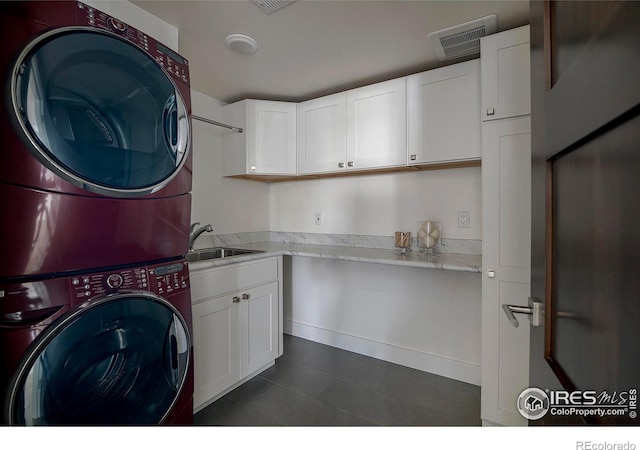 clothes washing area featuring a sink, cabinet space, visible vents, and stacked washer / drying machine