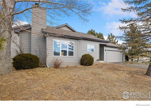 view of front of home featuring an attached garage, a chimney, and concrete driveway