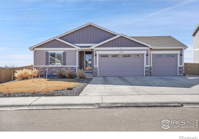 view of front of property with a garage, a shingled roof, fence, concrete driveway, and stone siding