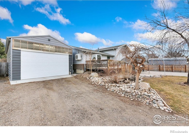 view of front of property featuring driveway, an attached garage, fence, and a wooden deck