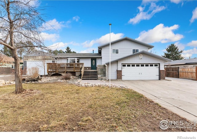 view of front of property with brick siding, concrete driveway, fence, a wooden deck, and a front yard