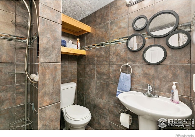 bathroom with a sink, tile walls, and toilet