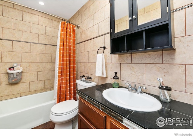 bathroom featuring shower / tub combo, toilet, backsplash, vanity, and tile walls