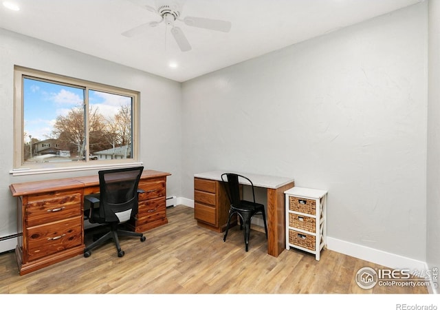 office space with light wood-style floors, baseboard heating, ceiling fan, and baseboards