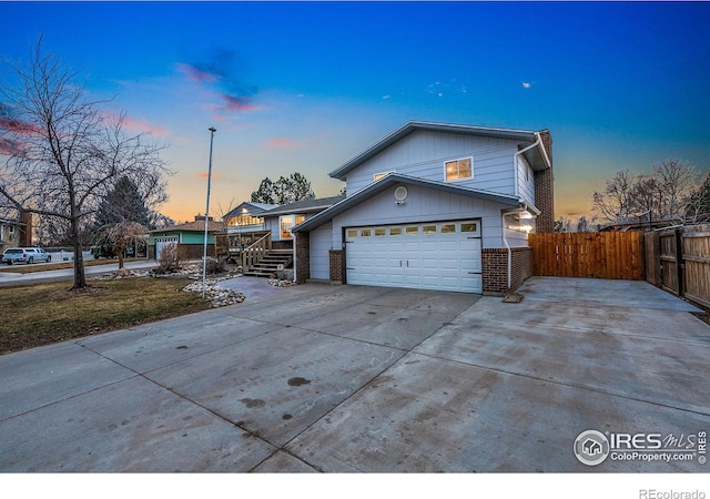 view of front of house with a garage, concrete driveway, brick siding, and fence