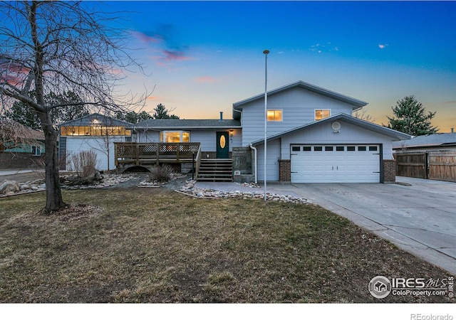 tri-level home with driveway, an attached garage, fence, a yard, and brick siding