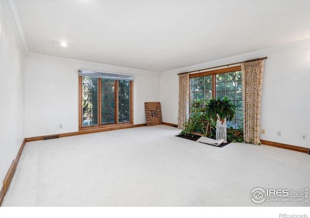 carpeted spare room with ornamental molding, visible vents, and baseboards