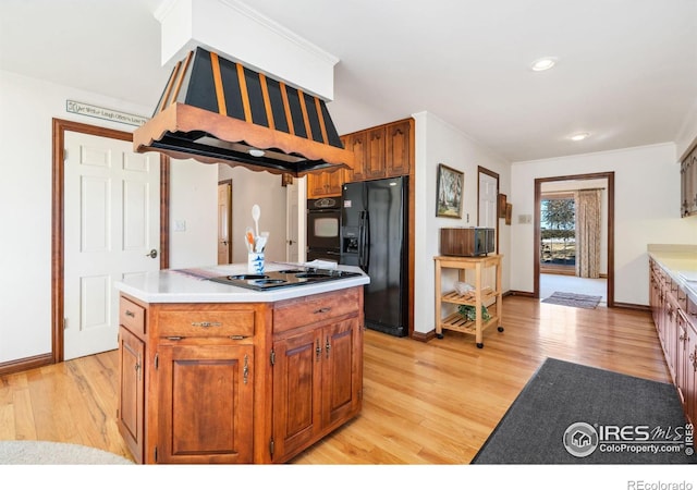 kitchen with cooktop, light countertops, black fridge with ice dispenser, and light wood finished floors