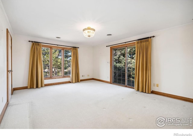 carpeted spare room with baseboards and crown molding