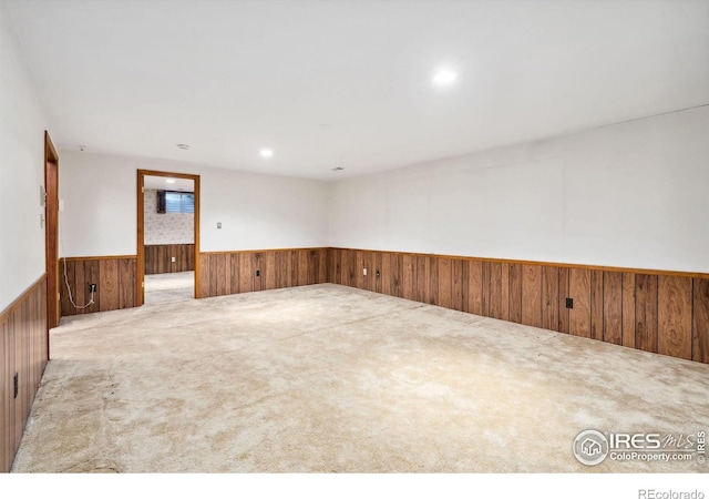 carpeted empty room with recessed lighting, a wainscoted wall, and wooden walls