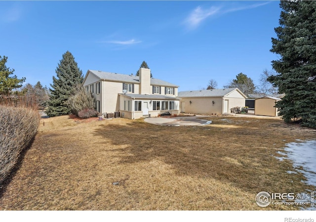 back of house featuring a storage shed, an outdoor structure, a lawn, and a patio