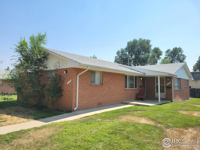 back of property with brick siding and a lawn