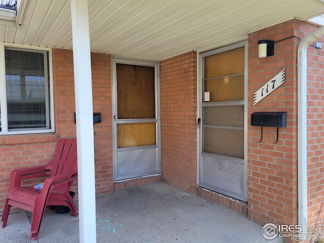 entrance to property featuring a porch and brick siding