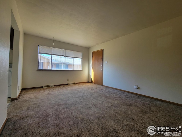 spare room featuring carpet, visible vents, baseboards, and washer / clothes dryer