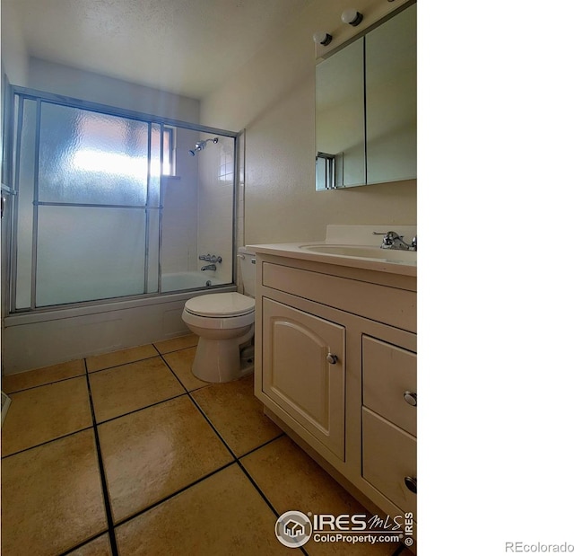 bathroom with bath / shower combo with glass door, vanity, toilet, and tile patterned floors