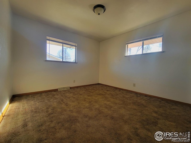 carpeted empty room featuring visible vents and baseboards