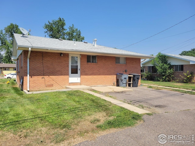 back of property with crawl space, brick siding, and a yard